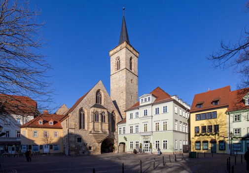 Blick auf die Ägidienkirche mit Turm, Tor zur Krämerbrücke und den umliegenden Häusern mit Restaurants, Cafés und Geschäften